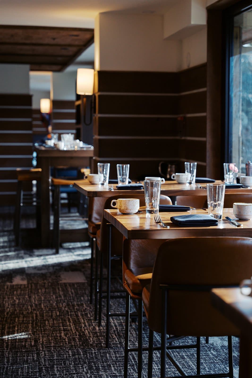 Multiple restaurant tables with seating and place settings