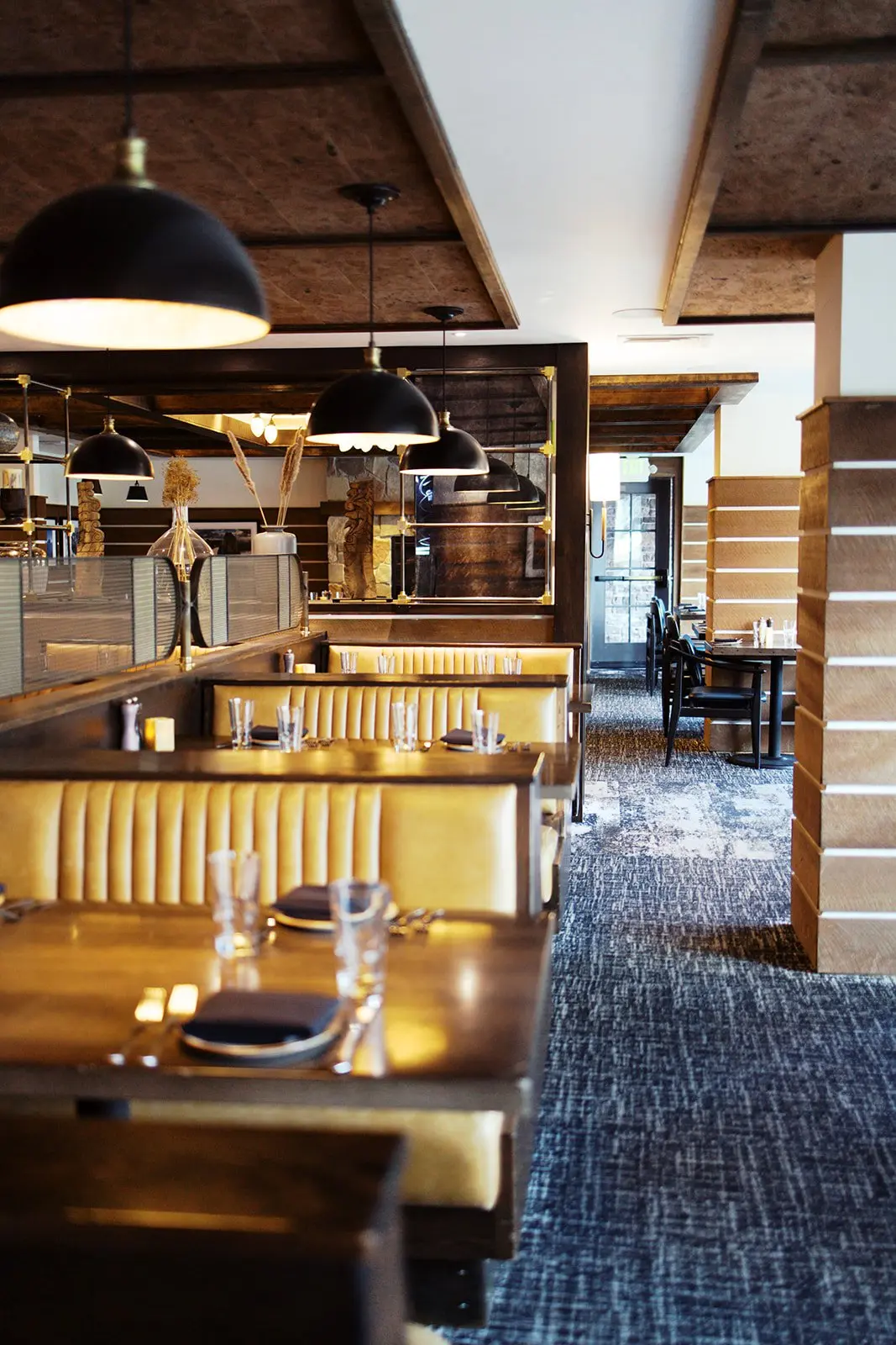 A photo of restaurant booths on the right and in the background on the left, multiple tables with chairs