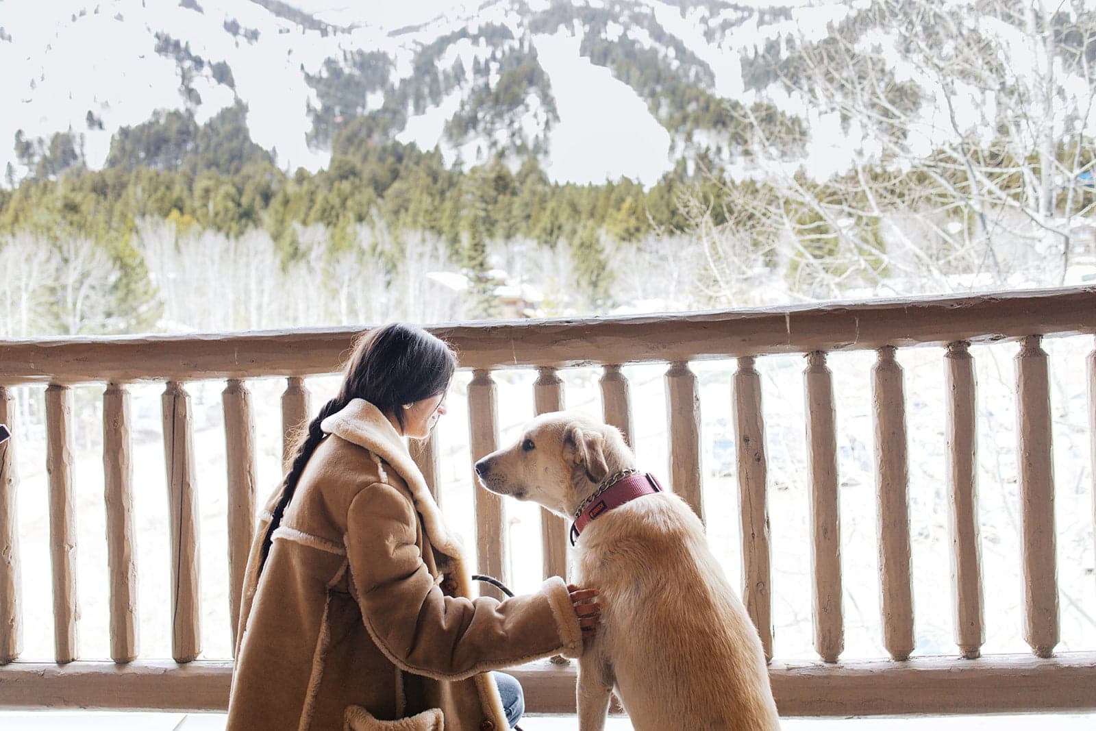 A photo of a woman and her dog sit outside on a balcony
