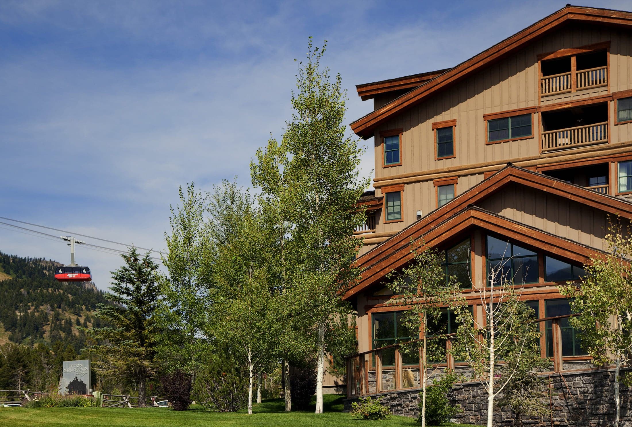 The exterior of Teton Mountain Lodge with an aerial tram and mountains in the background