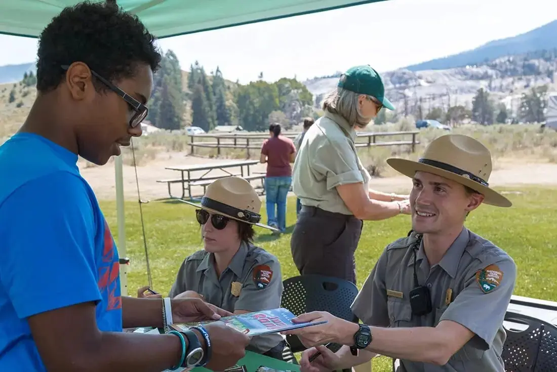 A National Park Service Ranger hands a child a book