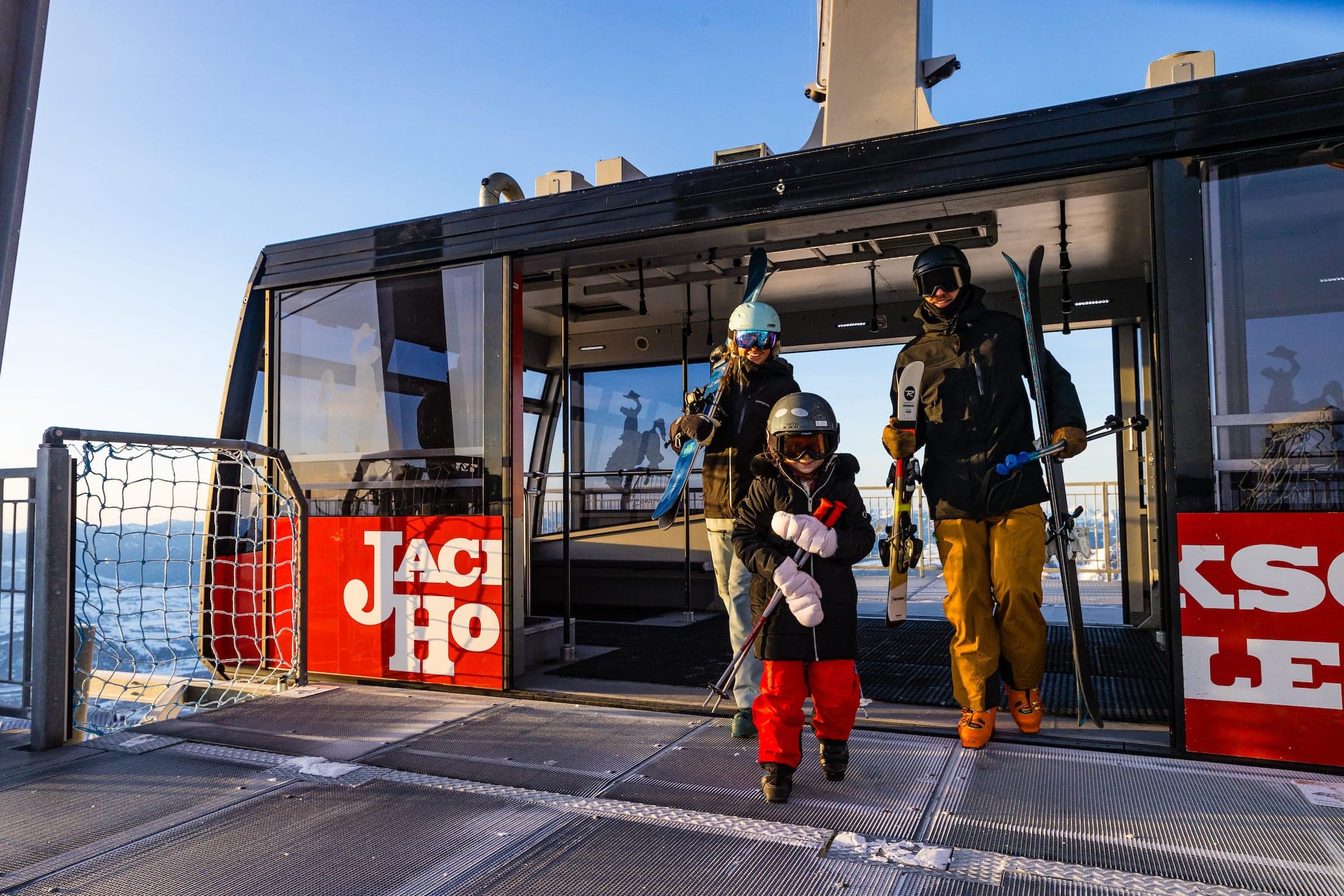 A family alights an aerial tram with skis
