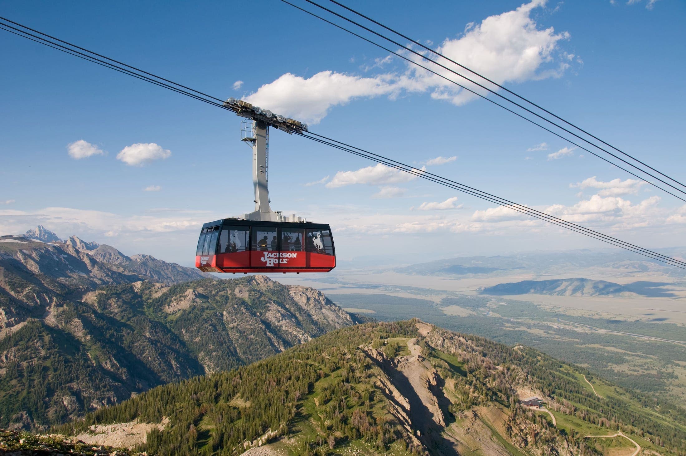 A photo of an aerial tram against the backdrop of a mountain and vast plains
